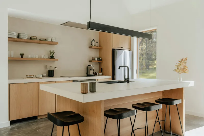 New kitchen with a white stone island bench, oak cabinetry, black bar stools and open timber shelving