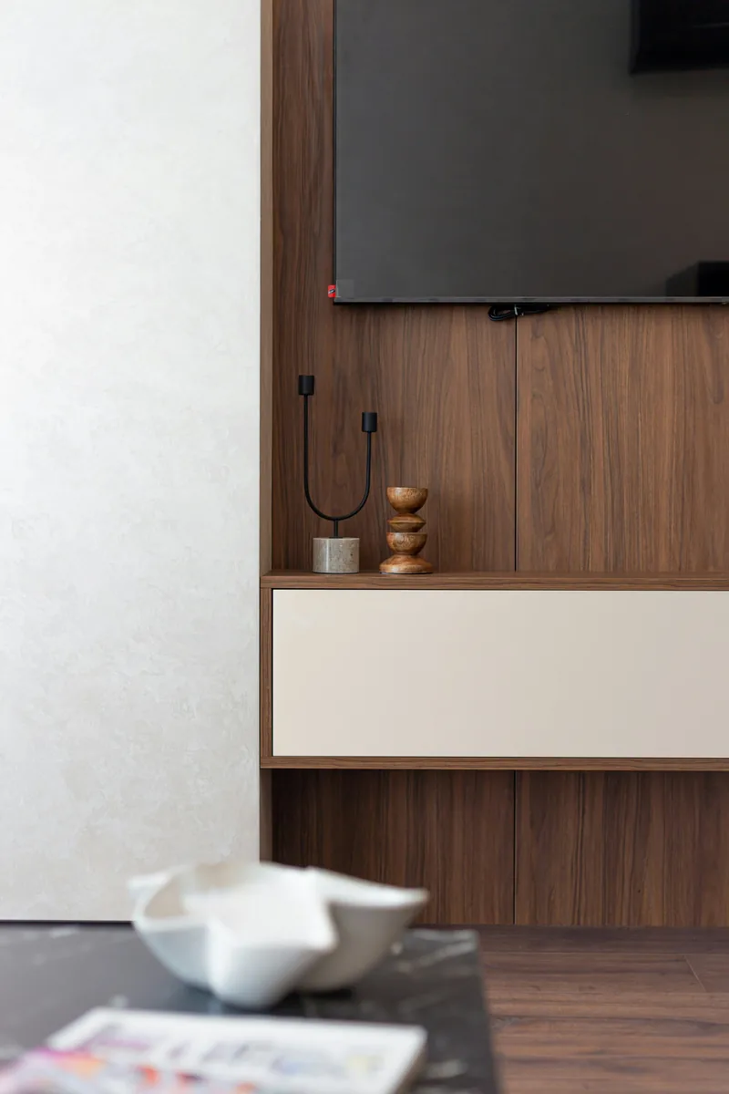 Custom walnut wall joinery with a floating cabinet and wall-mounted television in a living room, a marble side table in front